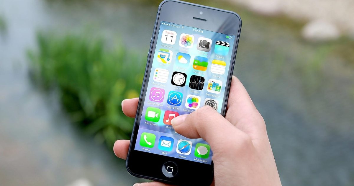 米哈社 App 首页界面在深色手机屏幕上的呈现，顶部是橄榄绿高亮的板块标签，下方滚动着图文混排的帖子列表，桌面背景为暗色木质纹理